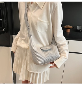 Close-up of silver pleated crossbody bag with metallic texture and adjustable strap