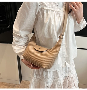 Detail showing beige pleated texture and leather strap of the stylish shoulder bag