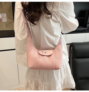Close-up of pink pleated hobo bag with vertical texture and shoulder strap on model