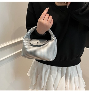 Close-up of silver pleated texture handbag with metallic finish and circular clasp