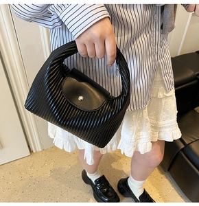 Detailed shot of black pleated PU leather handbag with silver metallic buckle detail