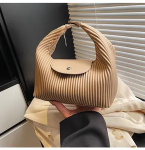 Detailed view of the elegant pleated texture and magnetic clasp on the apricot handbag