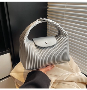 Detailed view of silver pleated handbag with metallic texture and snap button closure