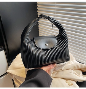 Detailed view of black pleated texture handbag with silver round button and PU leather finish