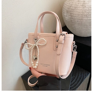 Détail du sac seau rose avec texture litchi, nœud en perles et breloque cœur
