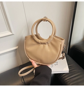 Detail of a chic half-moon saddle bag with dual metal ring handles and smooth vegan leather
