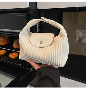 Detail shot of a creamy white pleated handbag with a silver metal buckle and zip closure