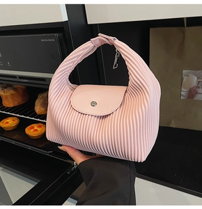 Detail of pink pleated handbag showing vertical texture and silver metal snap closure