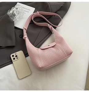 Detail of pink pleated hobo bag texture with adjustable strap on white fabric