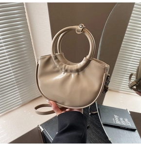 Chic beige pleated saddle bag with round handle and adjustable shoulder strap detail