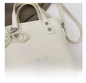 Vue détaillée du sac seau blanc avec breloque perle et lettrage de mode embossé