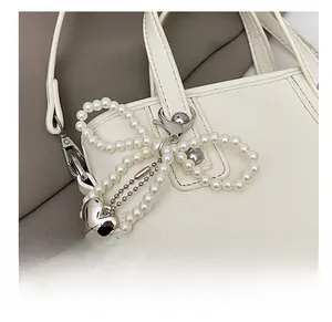 Détail d'un bijou de sac en perles avec pendentif cœur sur un sac seau en cuir blanc