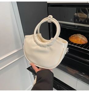 Detail of cream-white saddle bag with pleated PU leather finish and silver hardware