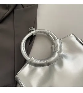 Detail of silver saddle bag showing metal ring handle and premium stitching quality