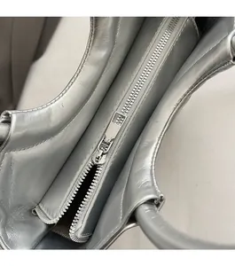 Detailed close-up of smooth silver metallic zipper and textured leather on saddle bag