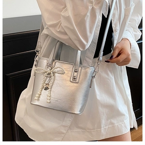 Détail du sac seau argenté avec nœud en perles, pendentif cœur et cuir froissé