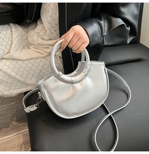 Detailed close-up of a metallic silver crescent saddle bag on a black leather seat