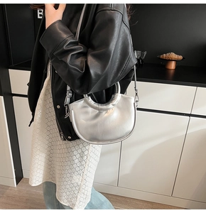 Detail of silver metallic crescent bag with sleek top handle and minimalist hardware