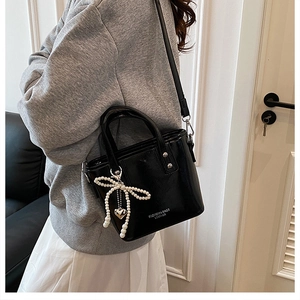 Détail du sac seau noir en similicuir avec nœud en perles et pendentif cœur en métal