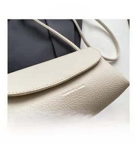 Detail of beige lychee textured leather crossbody bag with FASHION & BAGS lettering