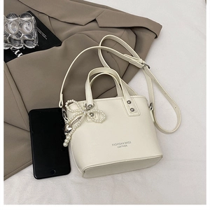 Détail du sac seau blanc crème avec breloque nœud perlé et bandoulière réglable
