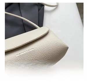 Close-up of beige lychee grain leather texture and precise stitching on the fashion bag