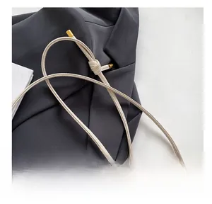 Close-up of cream leather shoulder strap with golden metal hardware and knot detail
