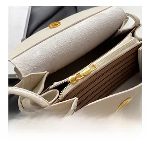 Detail of cream-colored pebble leather crossbody bag with gold zipper and striped lining