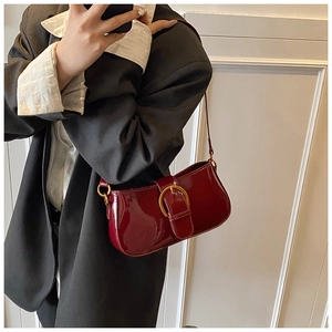 Détail du sac baguette en cuir verni rouge foncé avec boucle fer à cheval dorée