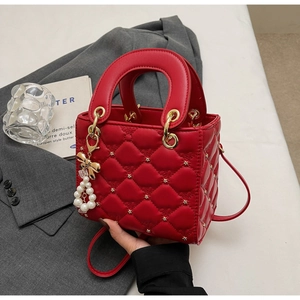 Détail du sac à main rouge matelassé avec charm nœud perlé et clous étoilés chics