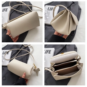 Detail of beige lychee grain shoulder bag with magnetic flap and elephant charm