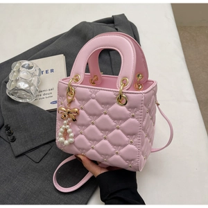 Détail du sac à main rose matelassé avec nœud doré et pendentifs en perles élégants
