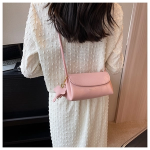 Pink lychee grain leather crossbody bag with a cute elephant charm shown on a model