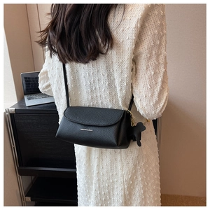 Close-up of black lychee grain leather crossbody bag with cute teddy bear charm