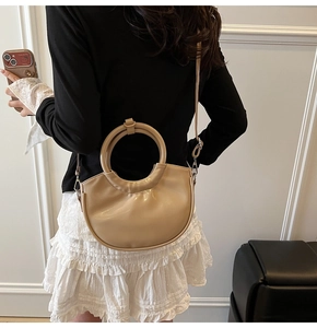 Chic beige crescent saddle bag with round handle shown as elegant shoulder crossbody bag
