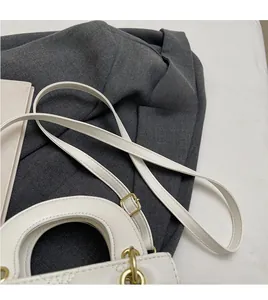 Détail de la bandoulière blanche réglable et lisse avec boucle en métal doré du sac