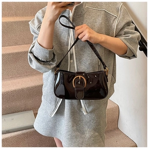 Vue détaillée du sac baguette en cuir verni foncé avec une grande boucle en métal doré