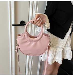Pink crescent-shaped leather handbag with silver hardware and a detachable shoulder strap