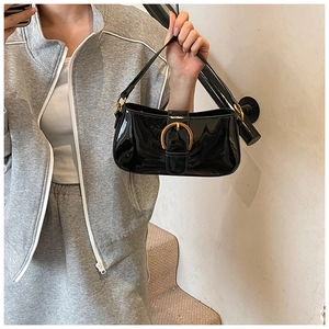 Détail du sac hobo en cuir verni noir brillant avec boucle en fer à cheval dorée