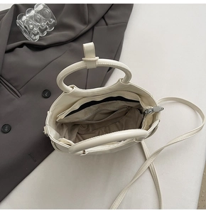 Detail view of cream white saddle bag showing internal zipper pockets and storage