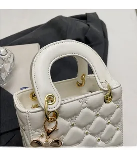 Détail du mini sac blanc matelassé avec clous étoiles dorés et pendentif papillon