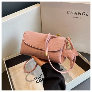 Detail of pink pebbled leather crossbody bag featuring an elephant charm and gold lettering