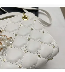 Détail du sac matelassé blanc avec ferrures étoiles et chaîne décorative en perles