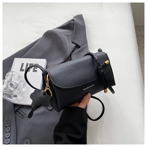 Detail of black litchi grain leather handbag with gold logo and elephant charm accessory