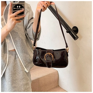 Détail d'un sac sous les aisselles en cuir verni marron foncé avec boucle fer à cheval