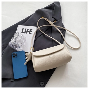 Detail of beige lychee grain leather bag with wing charm on a blazer background
