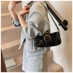 Détail d'un sac baguette en cuir verni noir avec boucle dorée en forme de fer à cheval