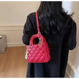Détail du sac à main rouge matelassé avec clous étoiles dorés et breloque en perle
