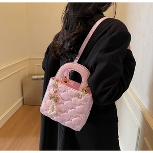 Détail du sac en cuir matelassé rose avec strass et pendentif nœud en perles