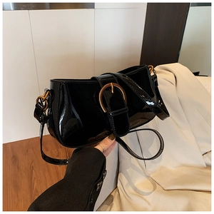 Gros plan détaillé du sac en cuir verni noir brillant avec une boucle fer à cheval dorée